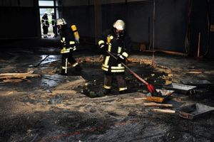 Abbrucharbeiten des verbrannten Hallenfußbodens unter Atemschutz.