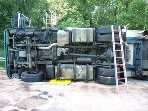 Der umgestürzte LKW liegt am Fahrbahnrand. Der geplatzte vordere Reifen, der den Unfall wahrscheinlich verursachte, ist zu erkennen.