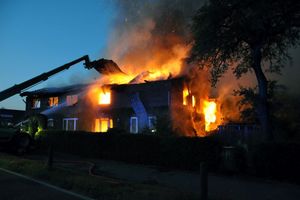 Das Brandobjekt von der Straßenseite aus betrachtet: mit einem Teleskopstapler wird das Dach eingerissen um besser an die Flammen zu gelangen.